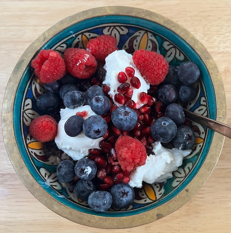 A pretty morrocan bowl full of porridge, flaxseed, sunflower and poppy seeds, blueberries, raspberries, pomegranate seeds and greek youghurt